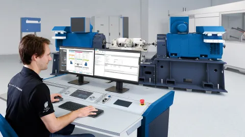 person sitting in front control desk which is in front of an e-axle testbed