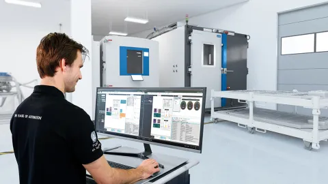 Man standing at a trolley operating battery automation software