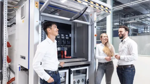 Team members discussing an advanced industrial testing and automation system in a high-tech facility.