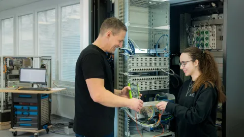 Two people work together on electronic components in a technical laboratory.