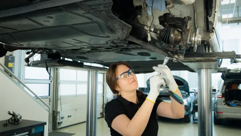 A person works on a vehicle on a lift in a workshop.