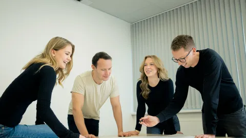 Several people collaborate on technical plans and drawings.