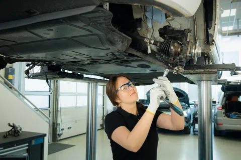 A person works on a vehicle on a lift in a workshop.